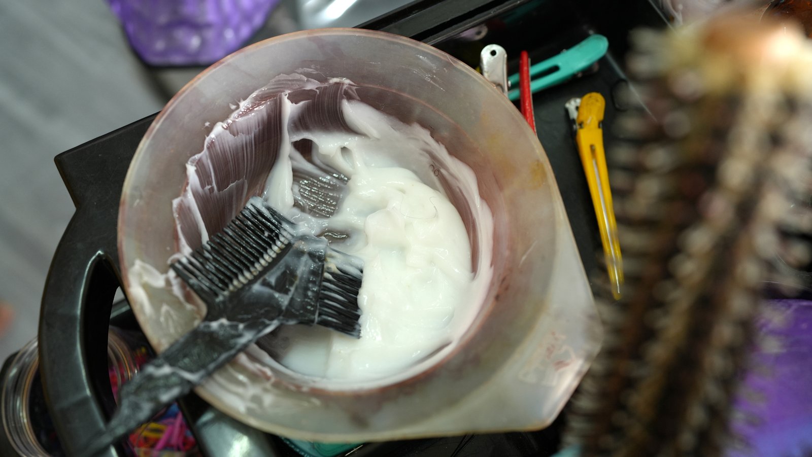 Leftover hair colour product and brushes in a salon mixing bowl, showing typical hair dye waste from manual mixing