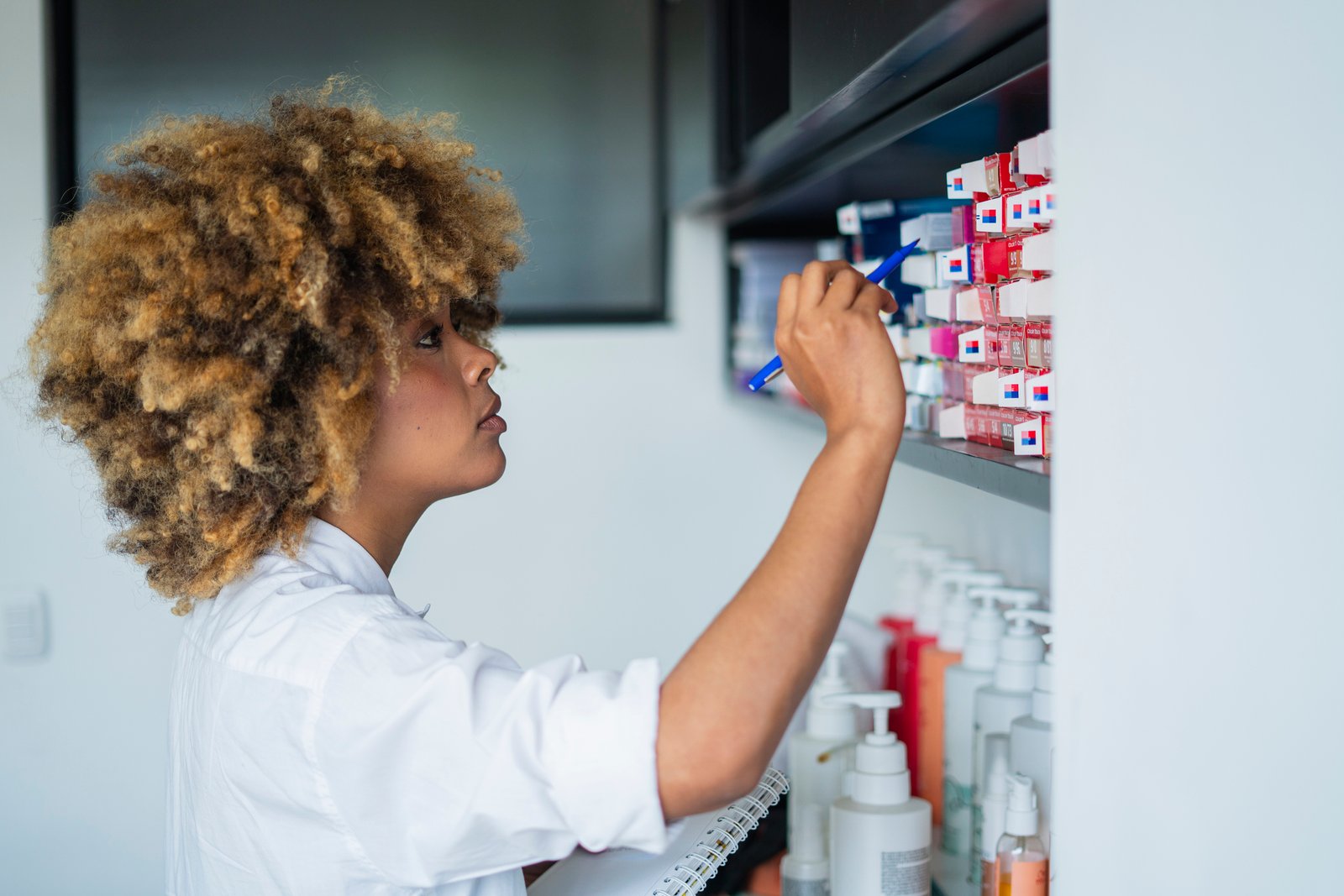 Salon owner checking hair colour product inventory on shelf, tracking product usage and cost